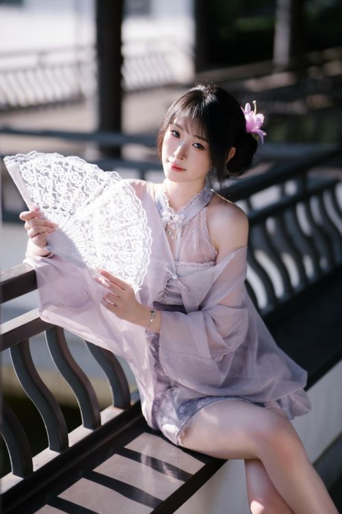 Free Elegant young woman in traditional attire holding a lace fan outdoors. Stock Photo