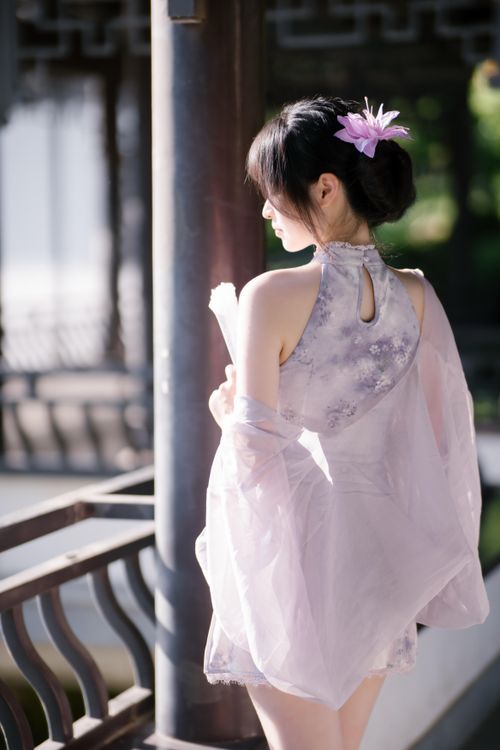 Free A woman in elegant traditional Asian dress holding a fan, standing outdoors. Stock Photo