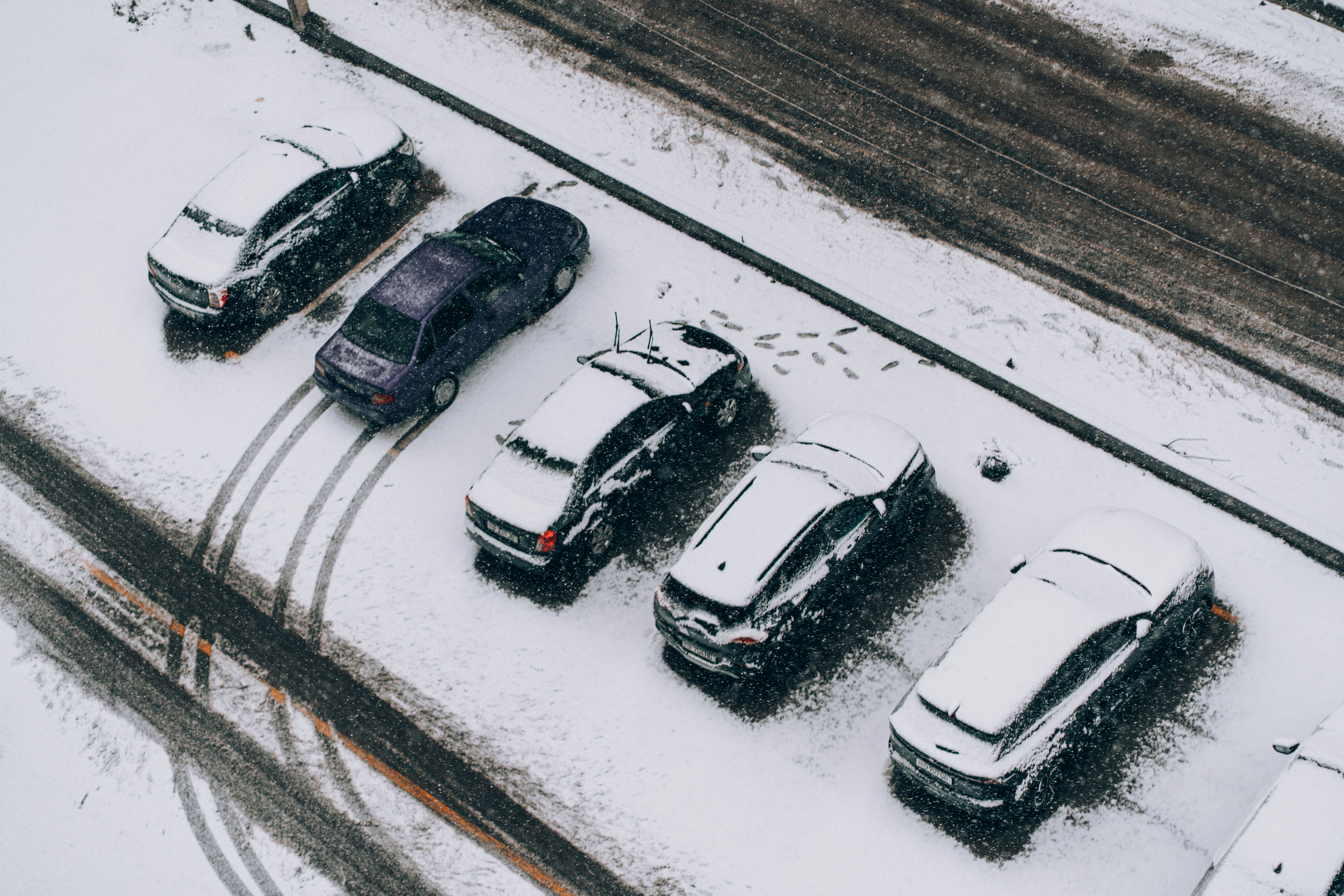 Aerial view of cars parked in a snowy lot during snowfall in Samarkand, Uzbekistan.