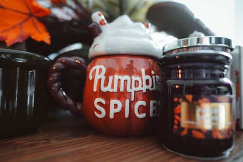 Free Rustic autumn setup featuring a pumpkin spice mug and candle for cozy home decor. Stock Photo