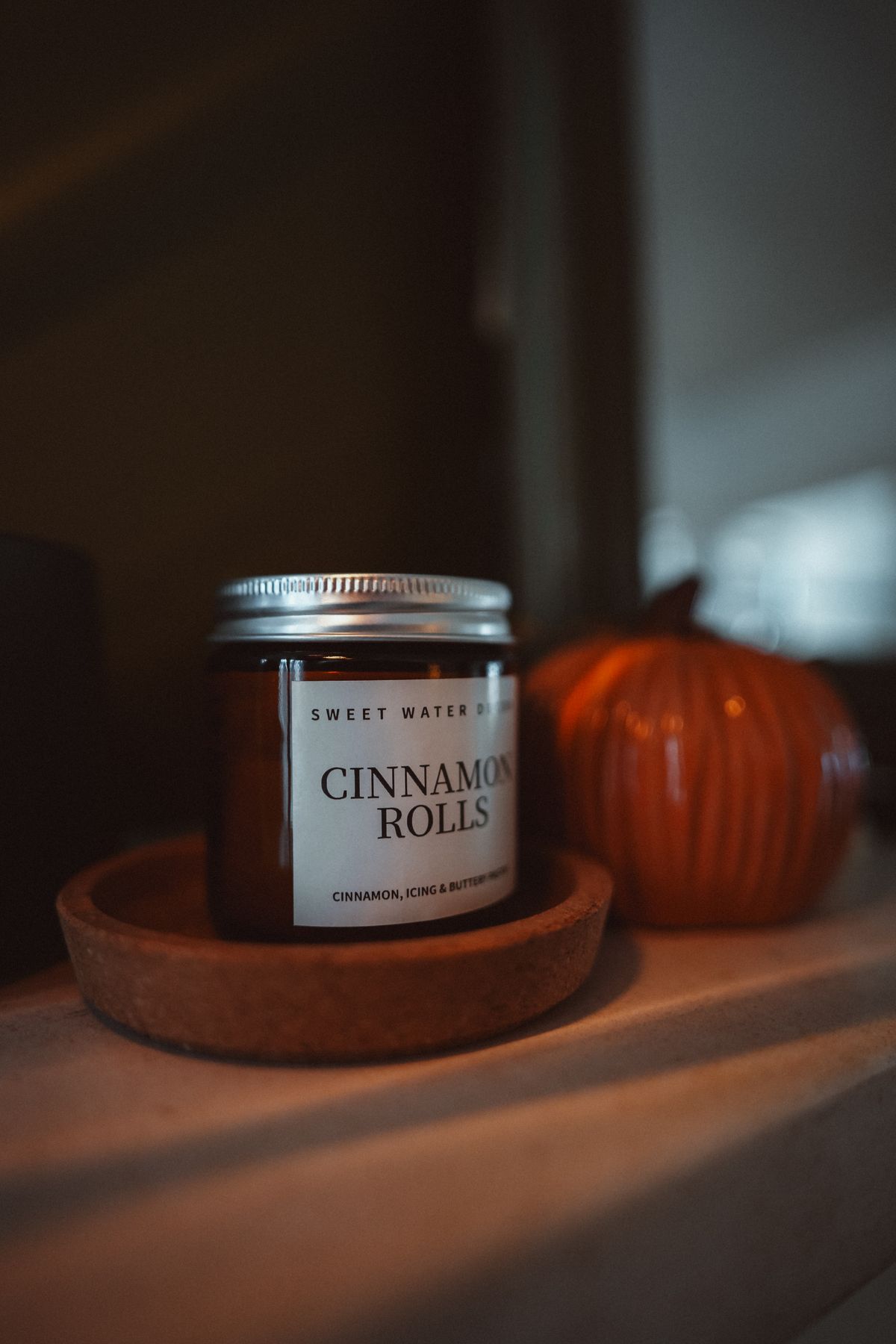 Warm autumn mantel decor with a cinnamon candle and pumpkin ornament
