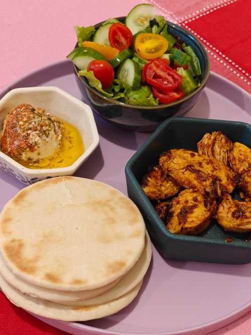 Free A vibrant Mediterranean meal with grilled chicken, fresh salad, and pita bread. Stock Photo