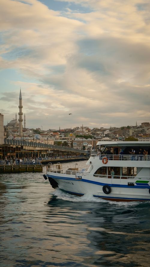 Free Scenic view of Istanbul's skyline featuring a ferry on the Bosphorus at sunset. Stock Photo