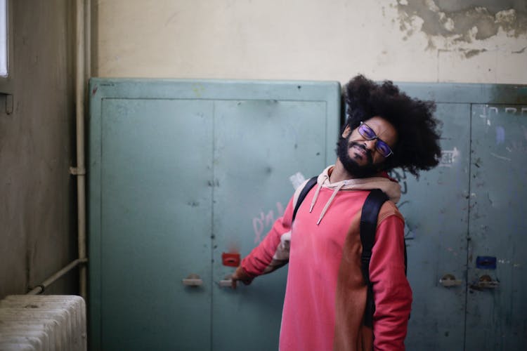 Man In Pink And Brown Jacket Standing Beside Gray Locker Door