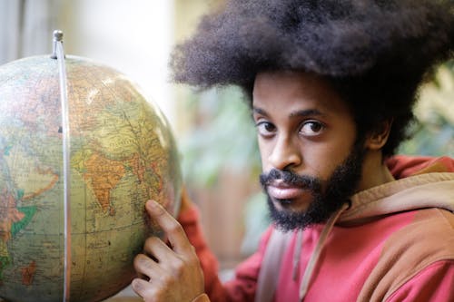 Man in Pink Hoodie Holding A Globe