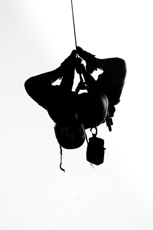 Free Dramatic black and white silhouette of a climber suspended upside down on a rope. Stock Photo