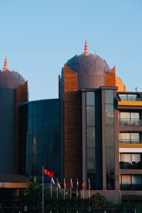 Free Modern hotel exterior with dome architecture and flags at sunset. Stock Photo