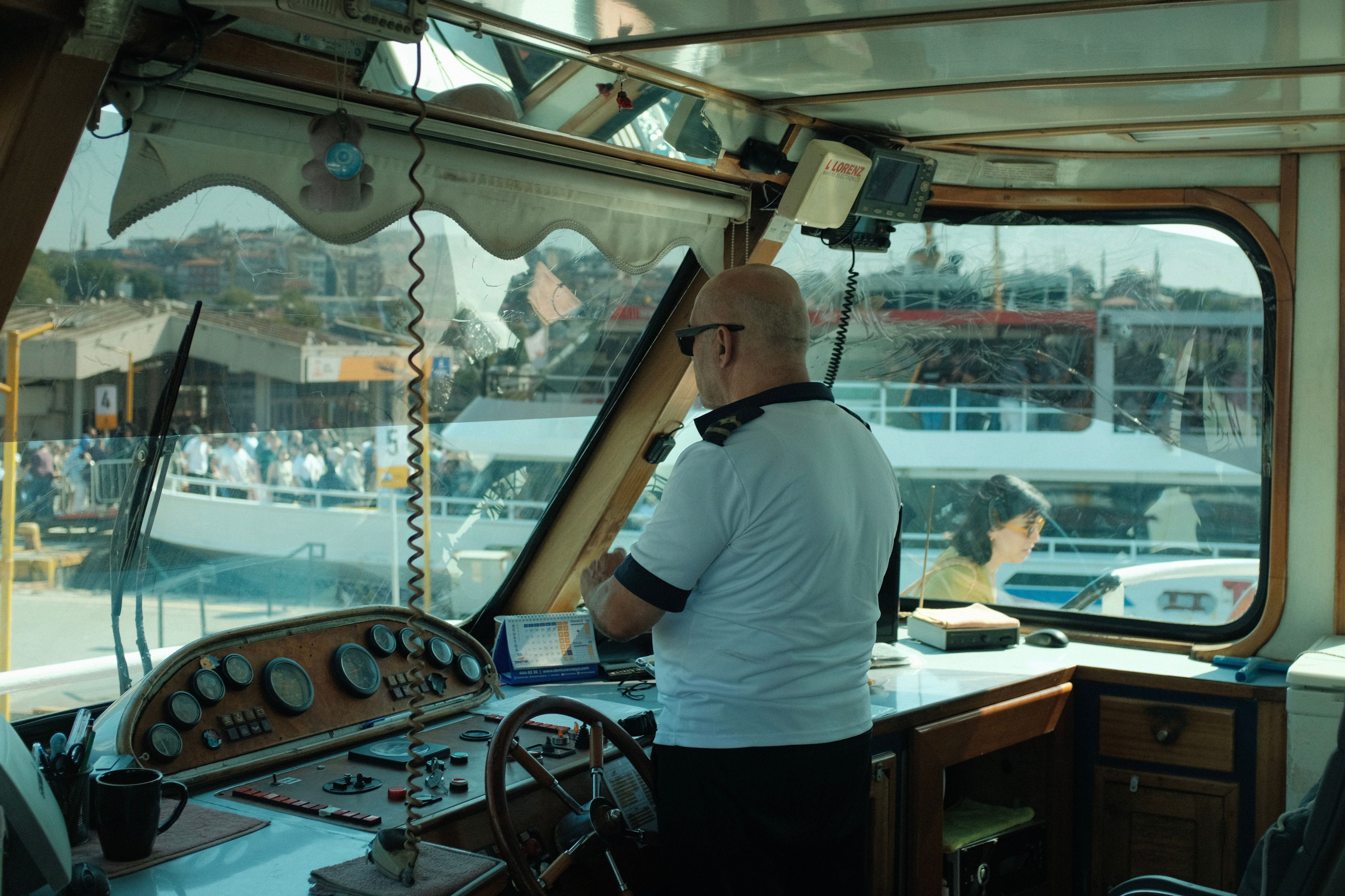 A boat captain navigates from inside a vessel's control room on a sunny day.