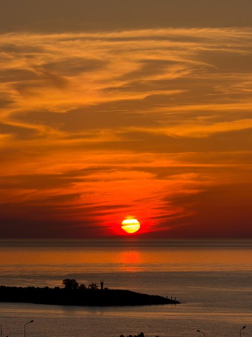 Free Beautiful sunset with fiery sky over a calm ocean, creating a serene atmosphere. Stock Photo