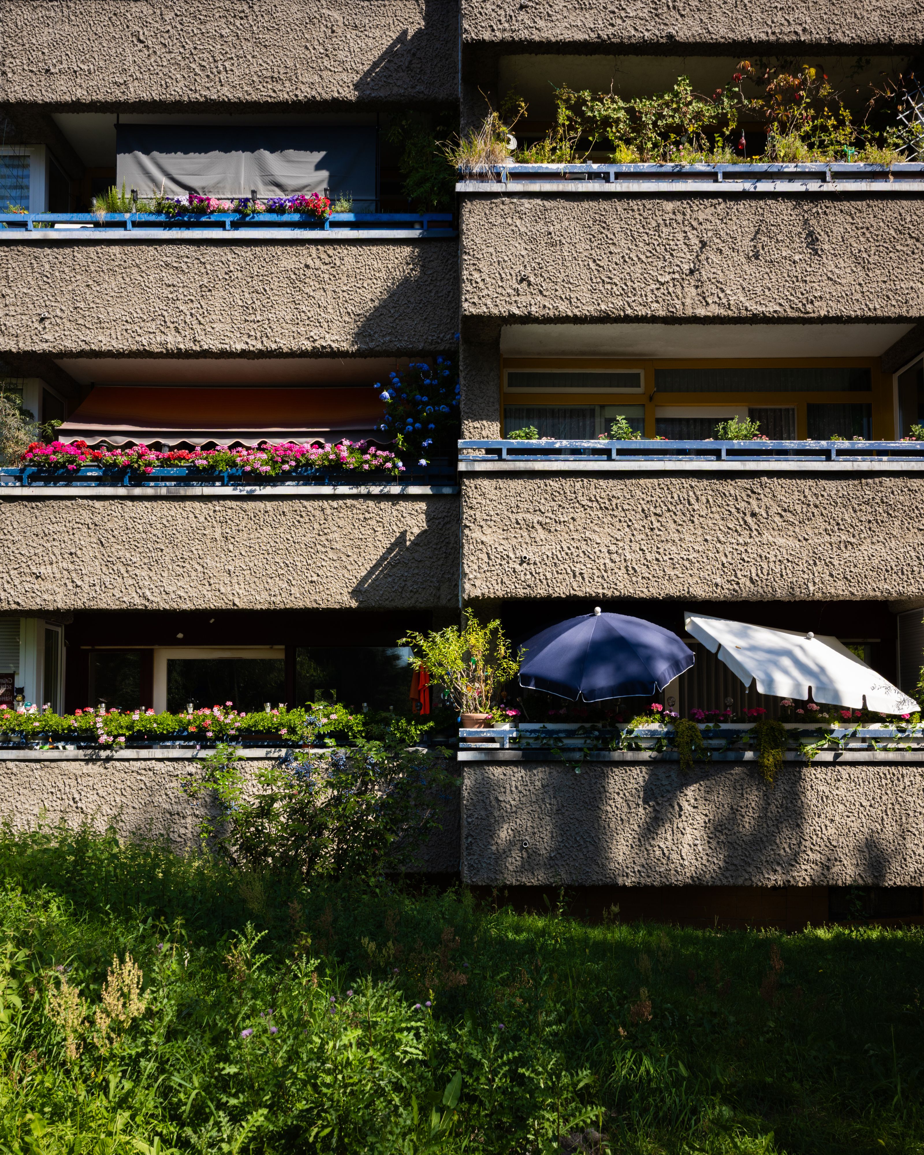 Vertical view of sunlight hitting Berlin apartment balconies with flowers and umbrellas.