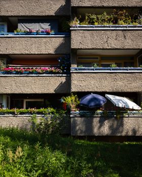Vertical view of sunlight hitting Berlin apartment balconies with flowers and umbrellas.