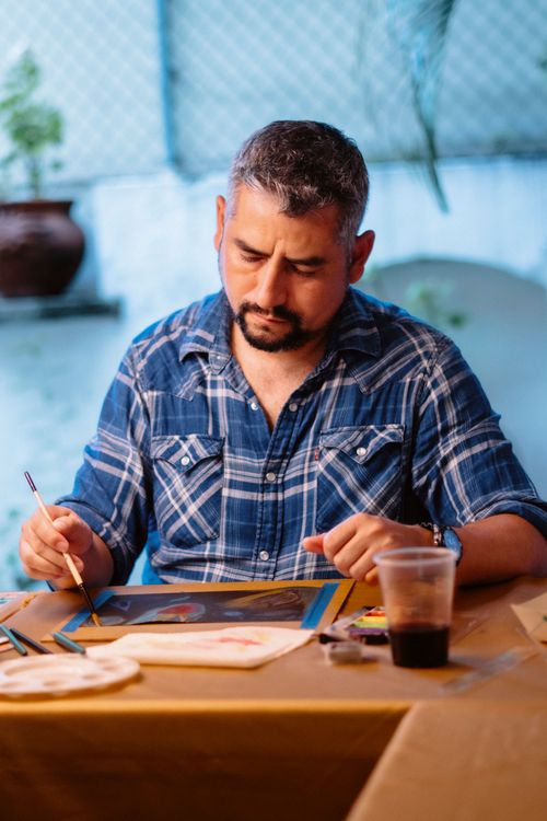Free Middle-aged man painting in a relaxed indoor setting, exhibiting focus and creativity. Stock Photo