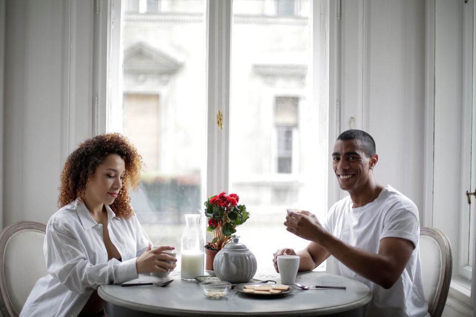 A happy couple enjoying a relaxed breakfast with coffee in a bright, cozy room.