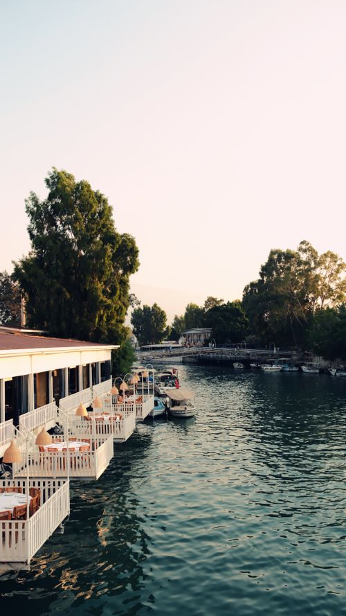 Free Charming riverside dining scene at sunset in Hatay, Türkiye with serene water and boats. Stock Photo