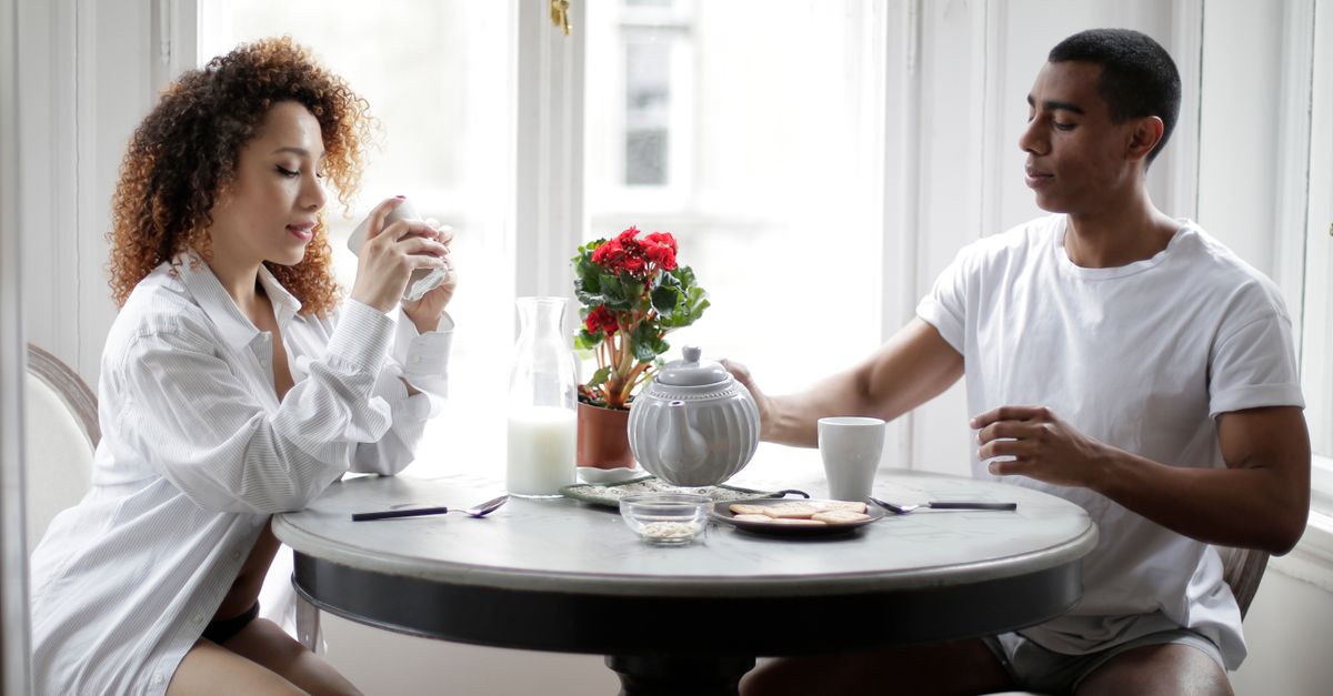 A couple enjoys a relaxed morning coffee and tea time indoors, fostering love and togetherness.