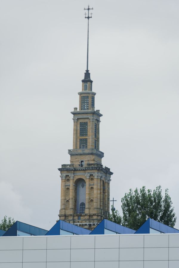 La tour Laboral aperçue derrière un arbre et des toits modernes, à Gijón