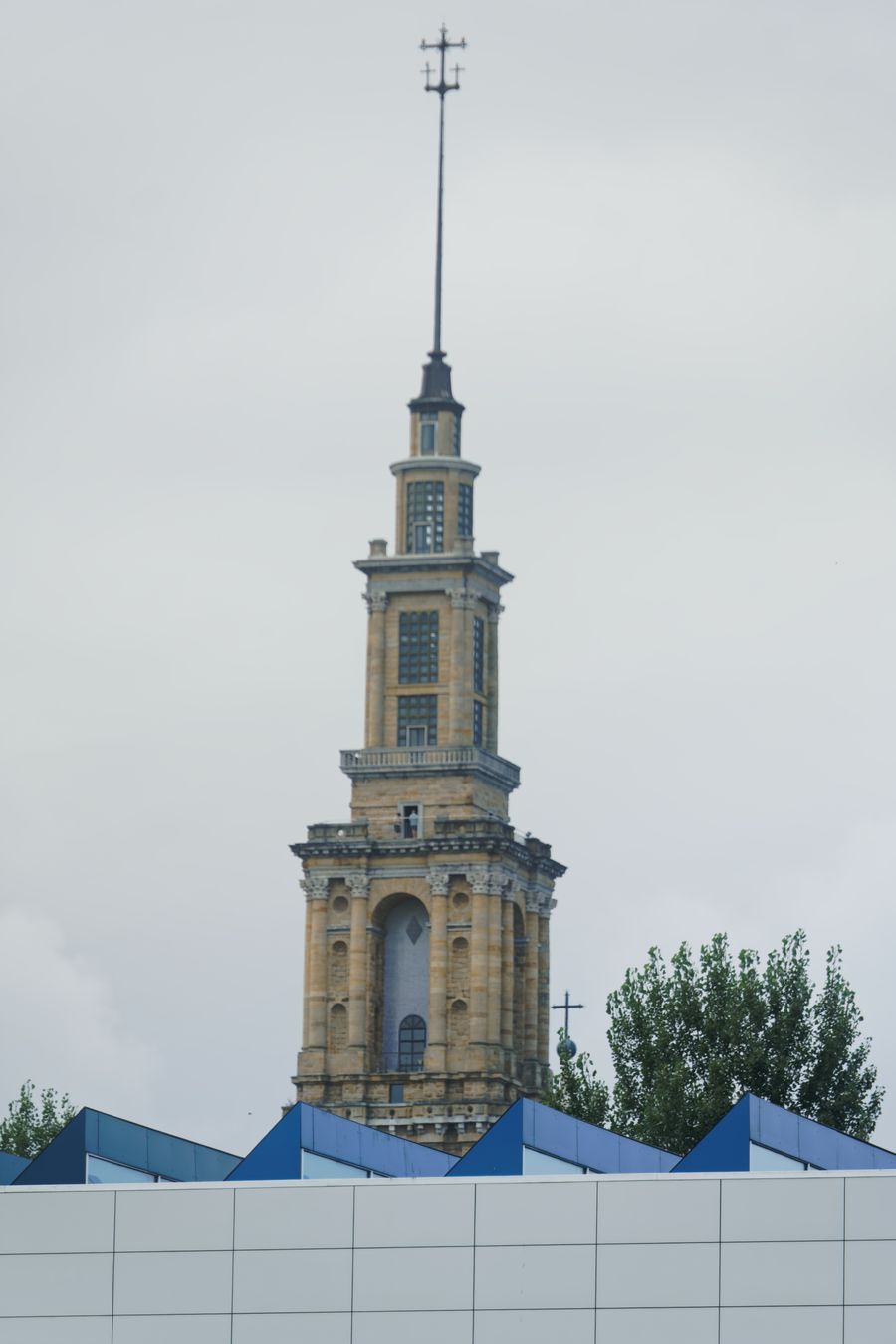 The Laboral tower seen past a tree and modern rooftops in Gijón