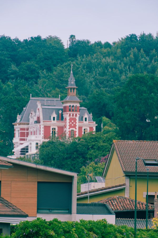 Villa ornée rouge et blanche sur un coteau boisé, à Gijón