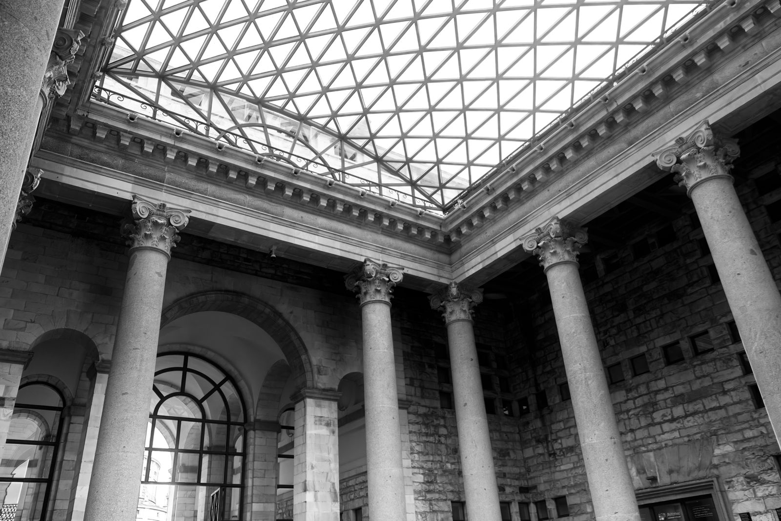 Grand atrium à colonnes corinthiennes et toit de verre, en noir et blanc