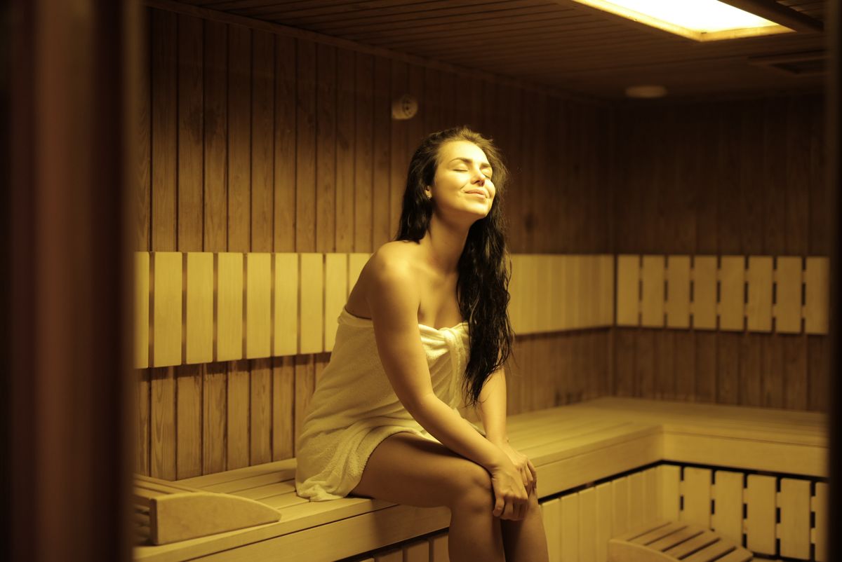 A calm sauna room with a person resting in a towel, used as a neutral visual for Korean spa recovery culture.