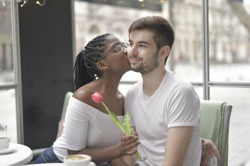 Free Woman Holding a Flower Kissing a Man Stock Photo