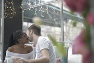 一对跨种族夫妇在一家挂着串灯的舒适咖啡馆里分享浪漫时刻
