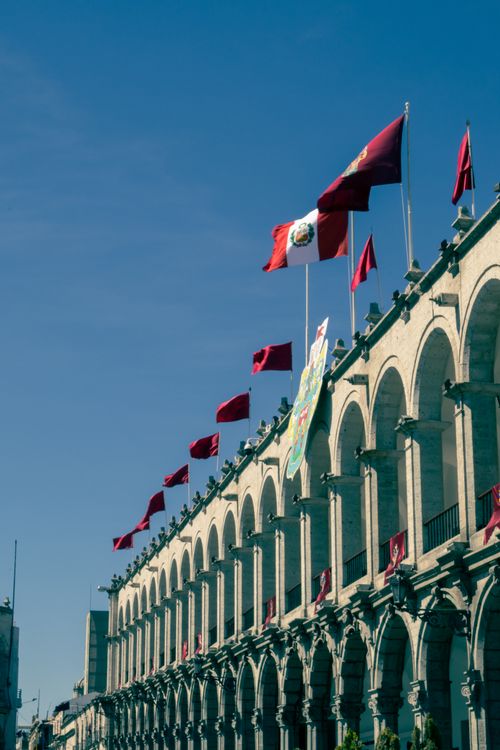 Free Beautiful historic colonnade with waving flags under clear blue sky in Arequipa, Peru. Stock Photo