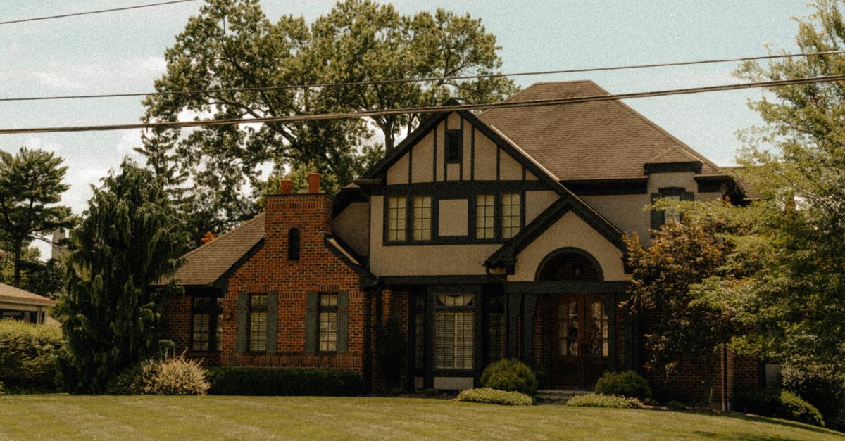 Beautiful Tudor-style home surrounded by green lawns and lush trees, exuding a classic and serene suburban vibe.