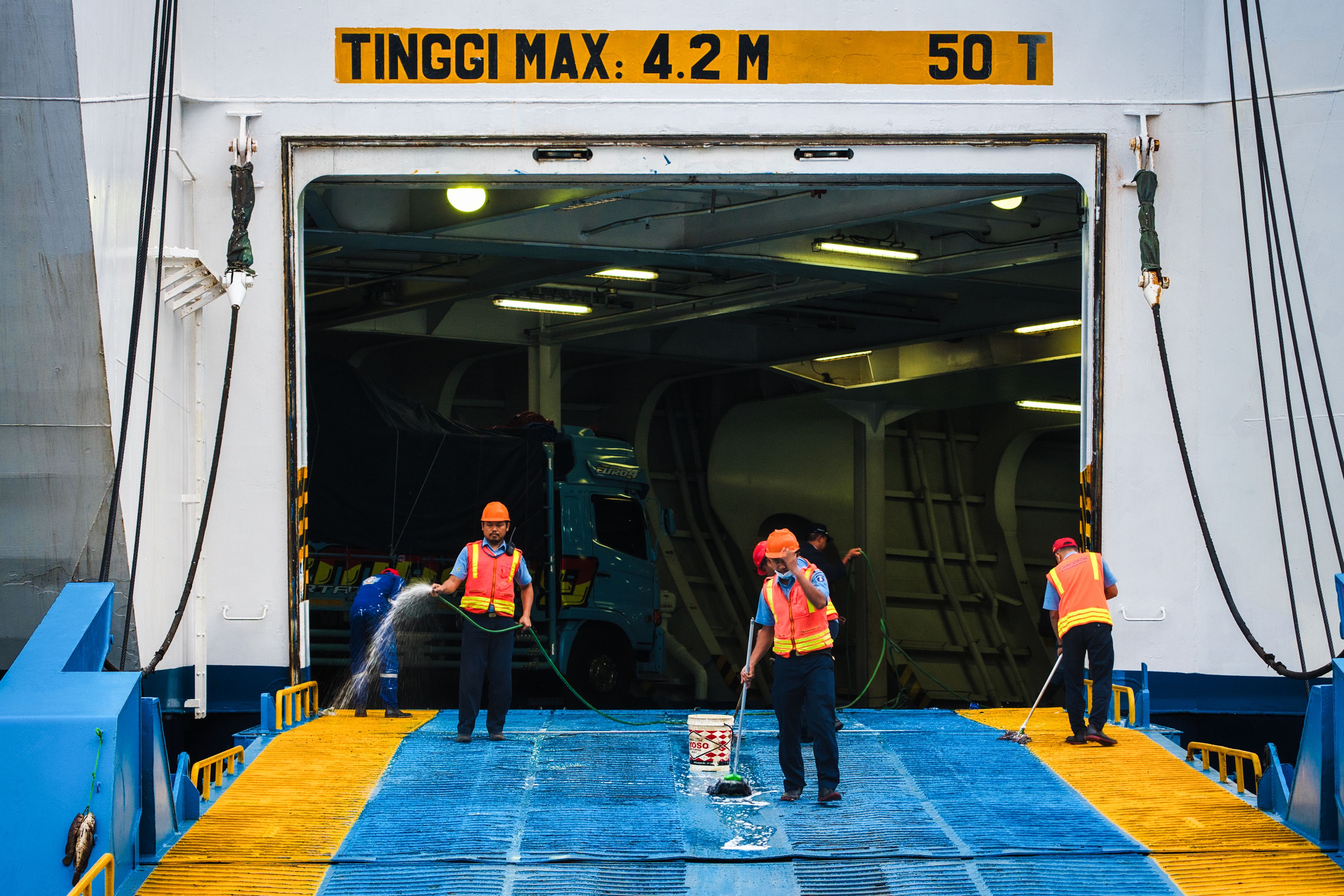Workers cleaning a ferry ramp at the port in Kalimantan Timur, showcasing teamwork in action.