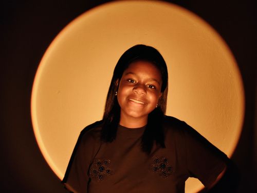 Free A woman with a warm smile stands in subtle lighting, creating a cozy atmosphere. Stock Photo