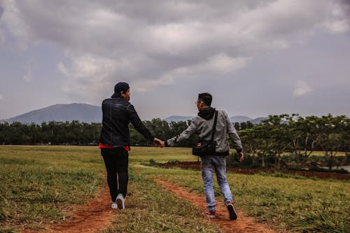 Pria Berpegangan Tangan Berjalan Di Lapangan Rumput Hijau