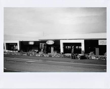 A vintage black and white photo of shops on a quiet street, capturing urban charm.