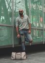 Man In Plaid Shirt and Tattered Jeans Leaning on Wall