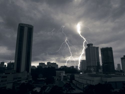 Free Striking lightning bolt over a city skyline showcases nature's power against modern architecture at twilight. Stock Photo