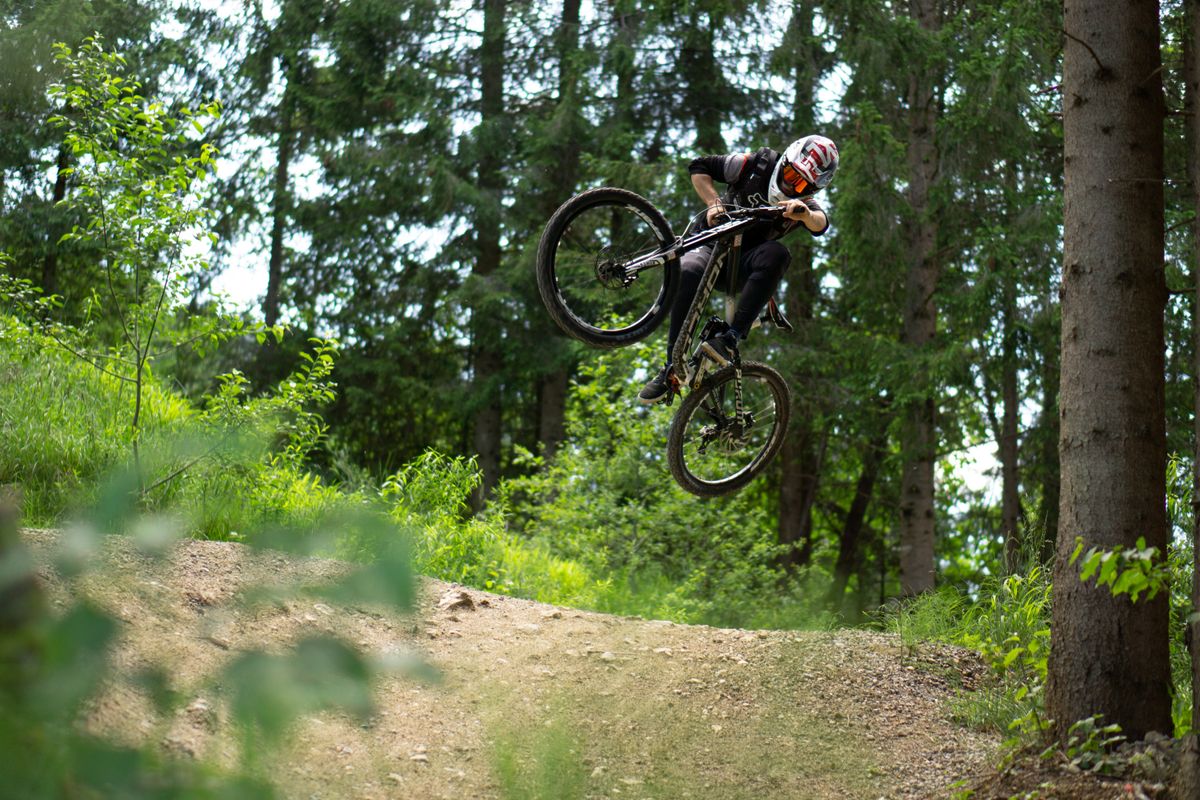 Mountain biker riding technical trail through forest demonstrating terrain where tire setup matters