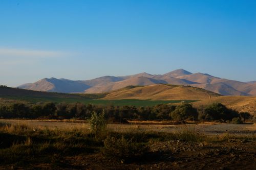 Free Peaceful view of rolling hills and mountains under a clear blue sky during daytime. Stock Photo