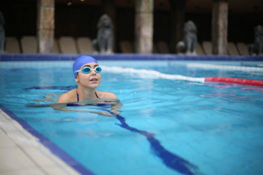 A woman with goggles swims leisurely in an outdoor pool, enjoying a summer day.