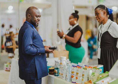 Free Business professionals interacting at a trade show in Accra, Ghana, showcasing products and engaging in conversation. Stock Photo