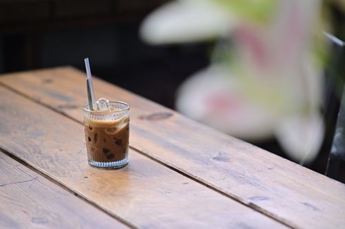 Free Close-up of iced coffee in a glass on a rustic wooden table outdoors, creating a refreshing summer vibe. Stock Photo