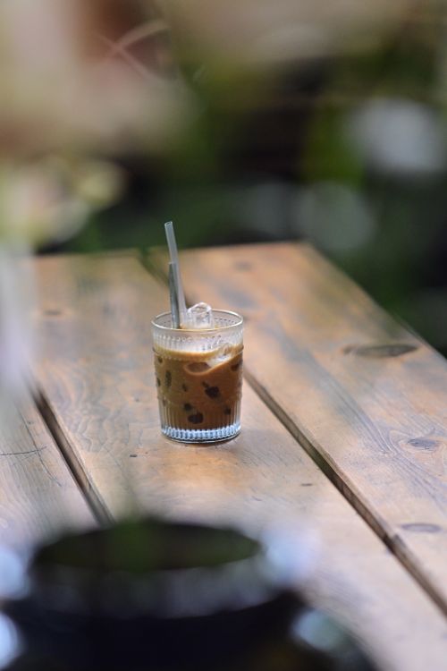 Free Close-up of iced coffee served on a rustic wooden table outdoors, evoking a calm and relaxing atmosphere. Stock Photo