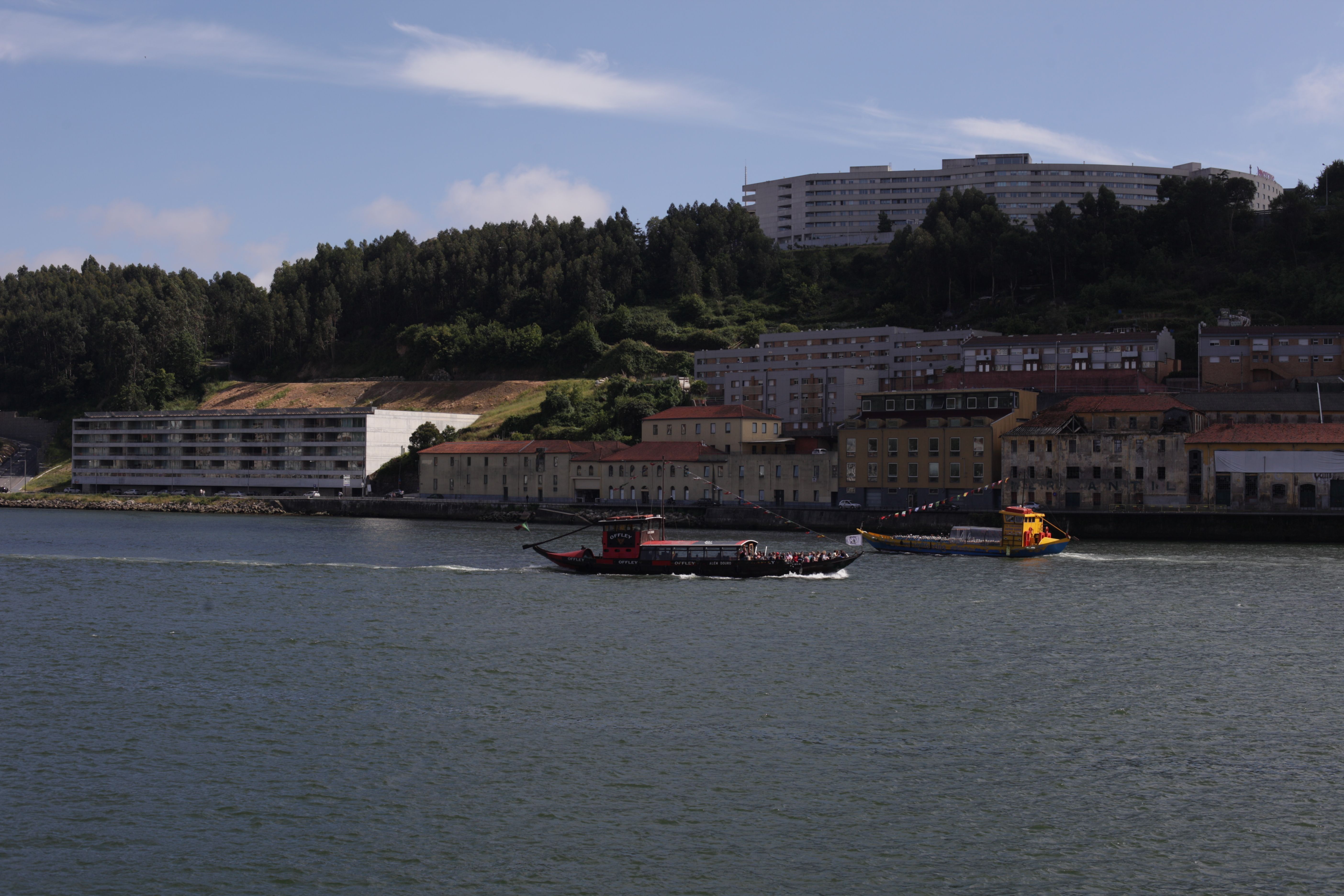Tourist boats navigate a scenic river flanked by city buildings and lush greenery, showcasing urban charm.