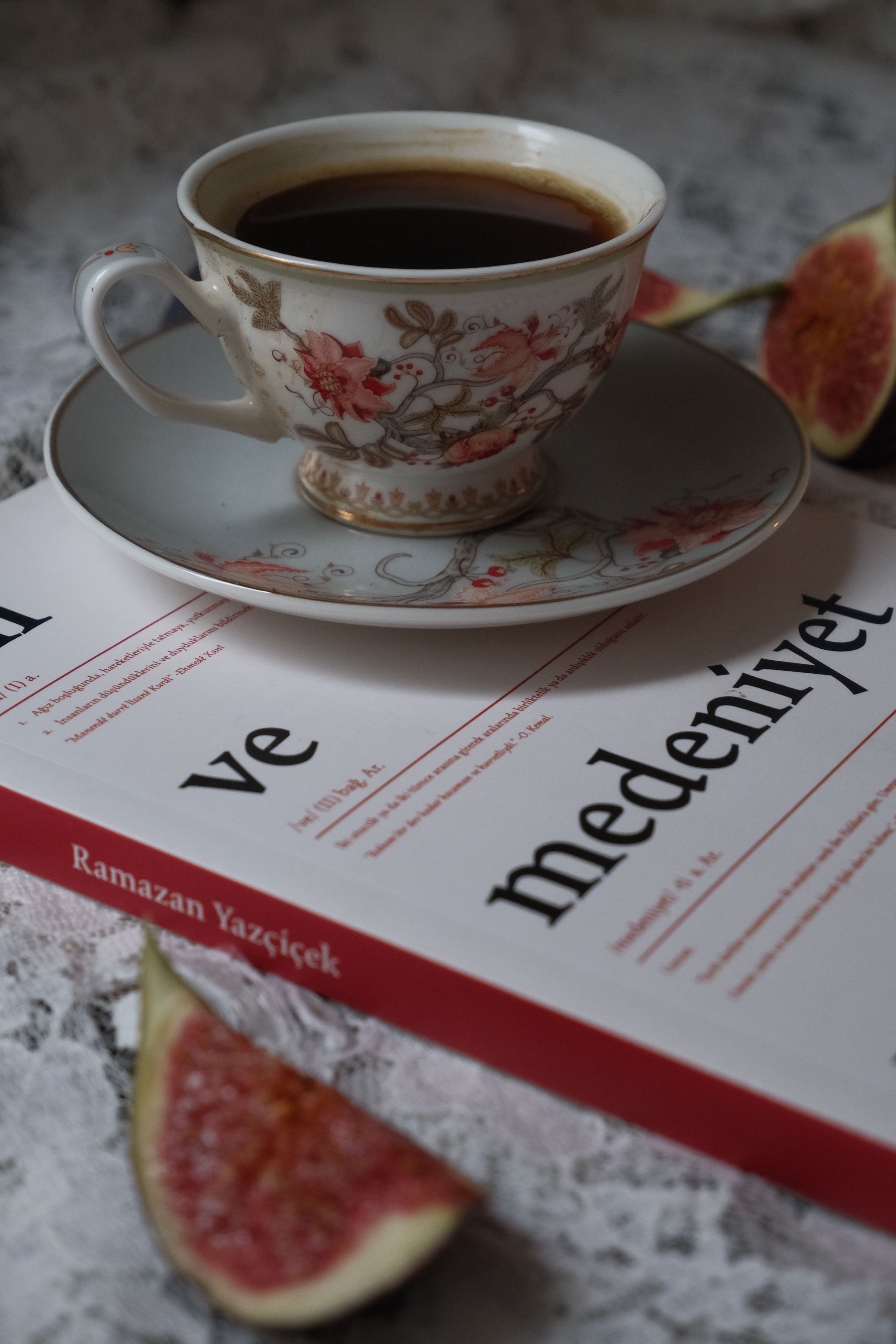 Vintage porcelain cup of tea with figs and an inspiring book.