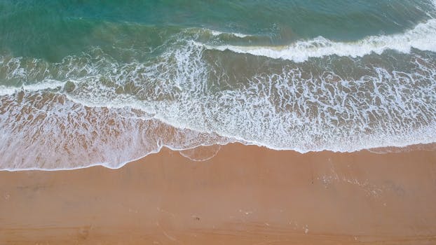 Aerial shot capturing the waves and sandy shore of a Brazilian beach.