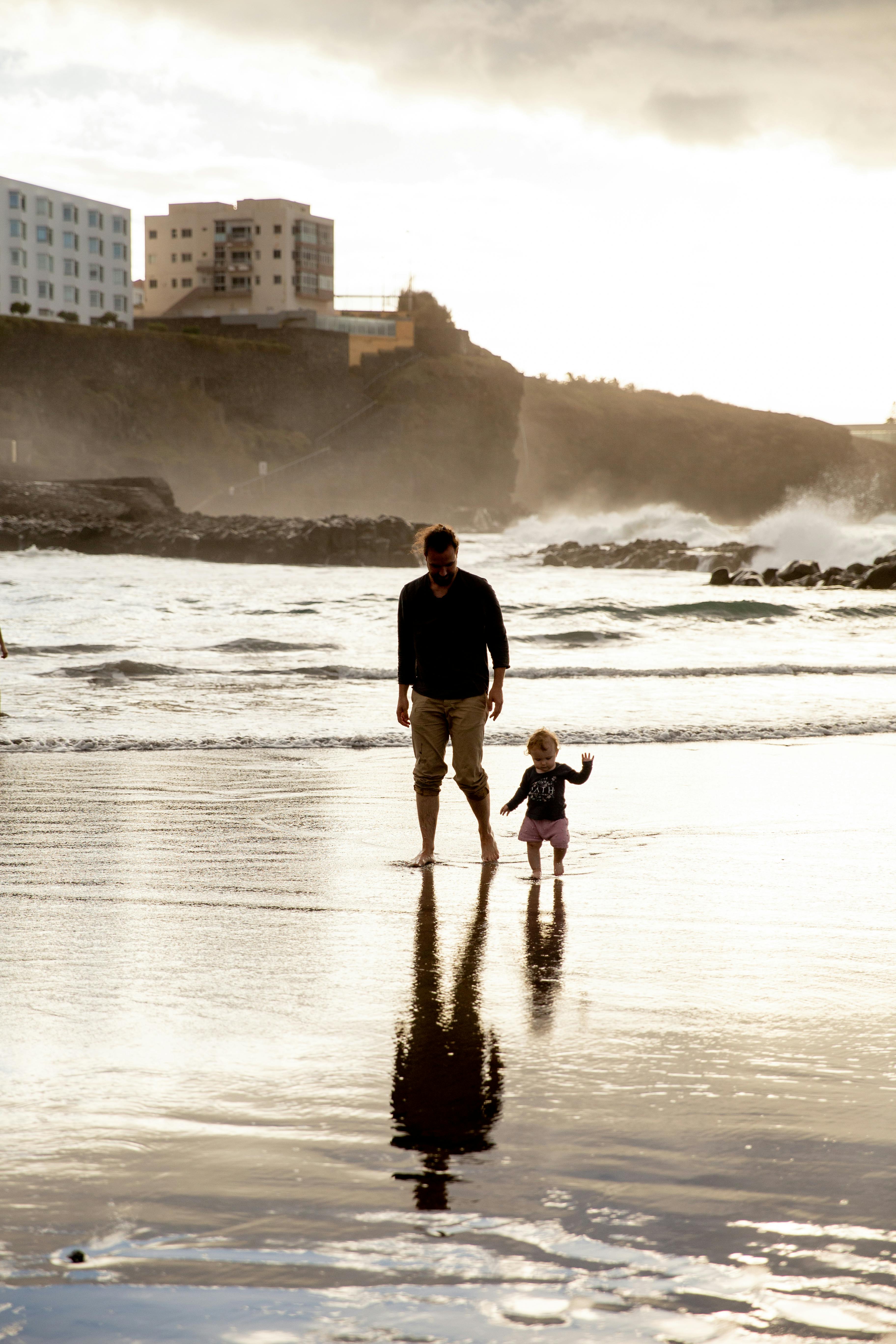 father and child walking on seashore