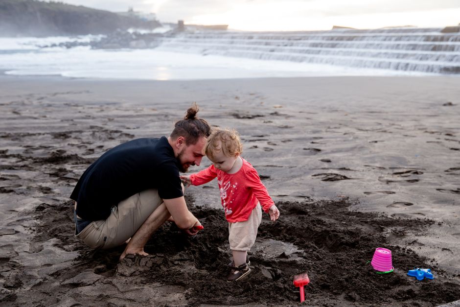 Un padre y un hijo disfrutando de un momento juguetón en una playa de arena junto al océano.