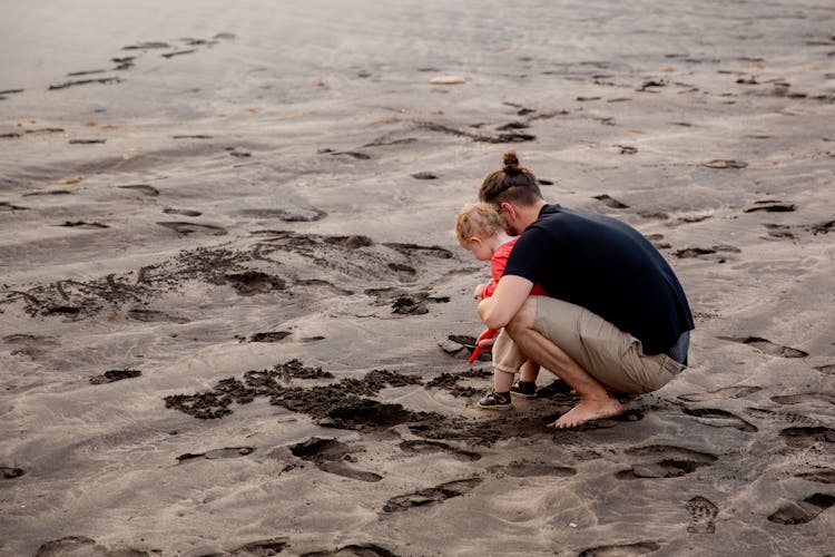 Father And Child Playing On Sand