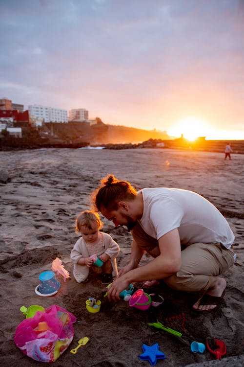 Free Father and Child Playing on a Sandy Beach at Sunset  Stock Photo