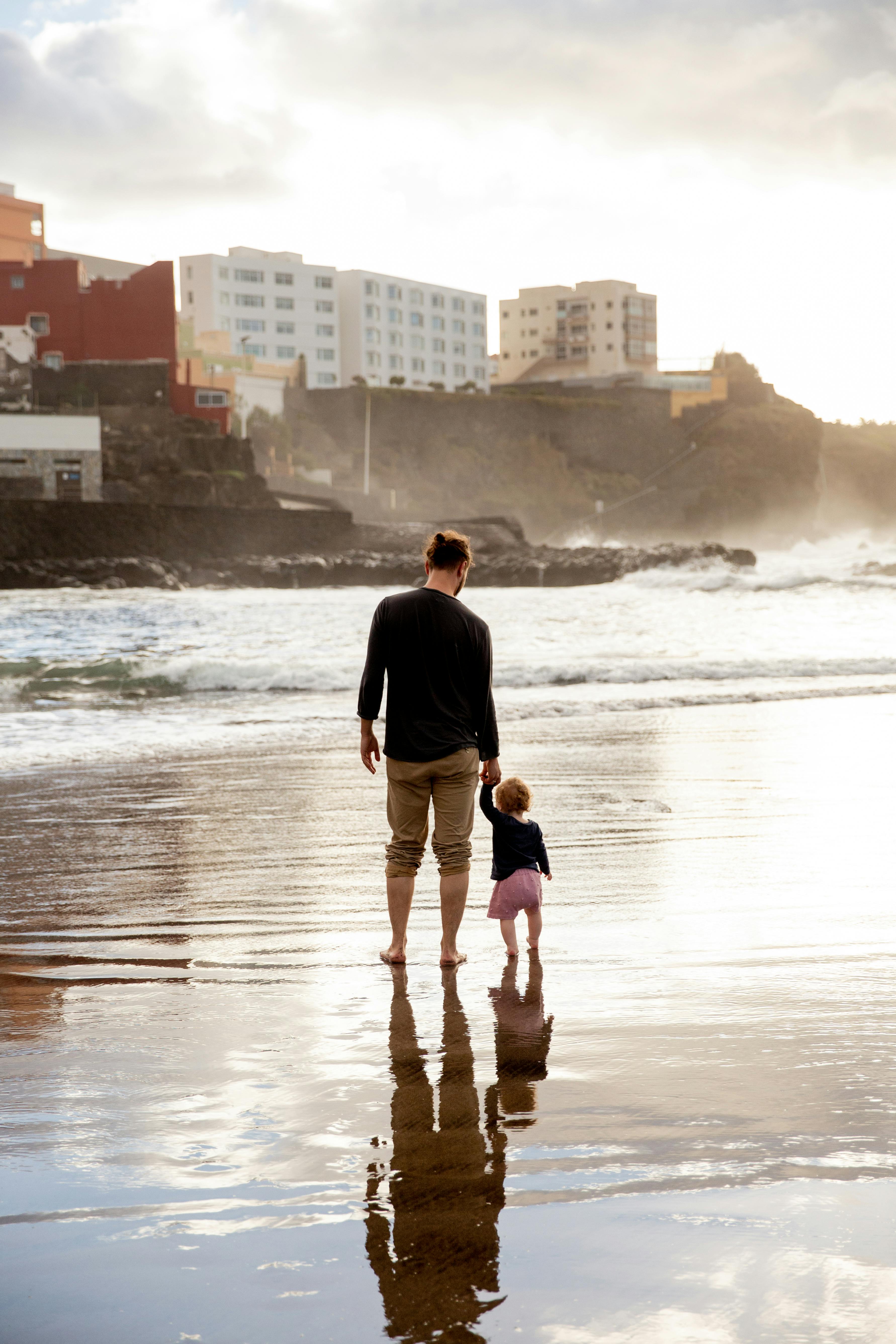 father and child walking on shore