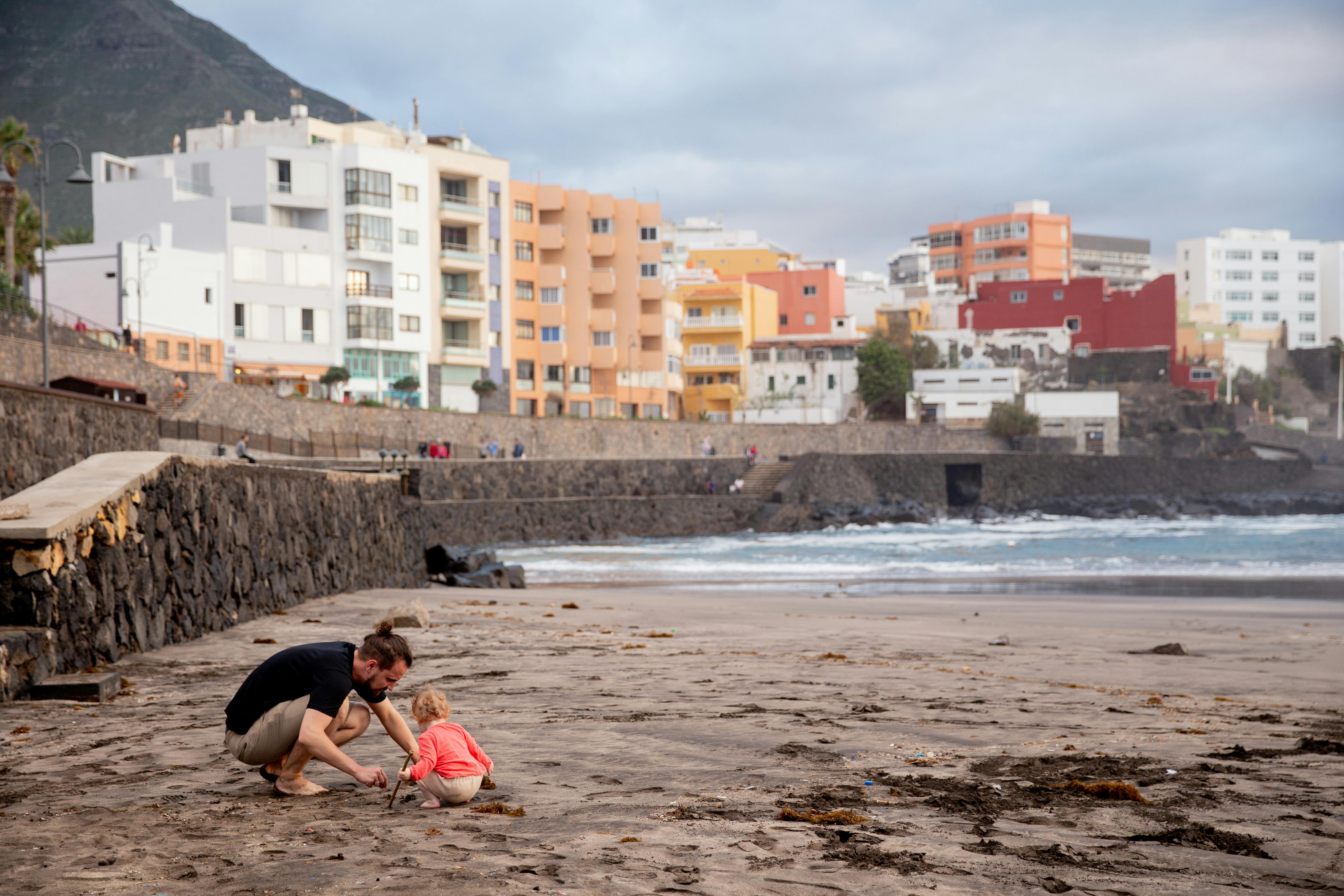 father and child playing on sand