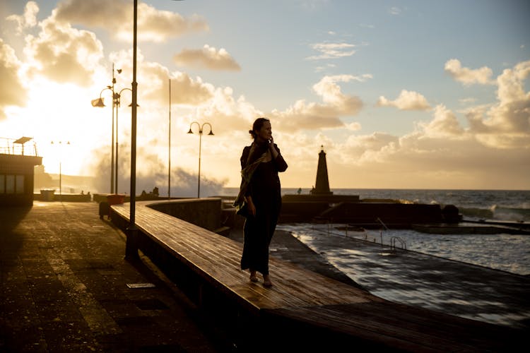 Woman Walking On Wooden Dock At Sundown